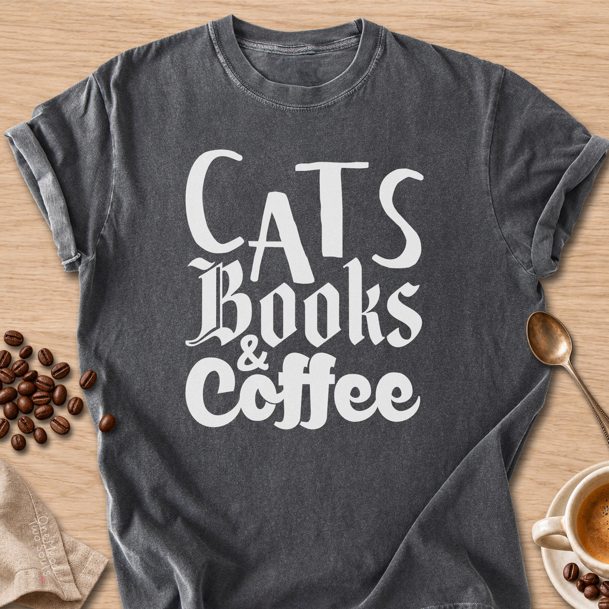 Pepper colored Comfort Colors 1717 cotton T-shirt, featuring a "Cats, Books & Coffee" funny cat design illustration. One Meow Two Souls brand.