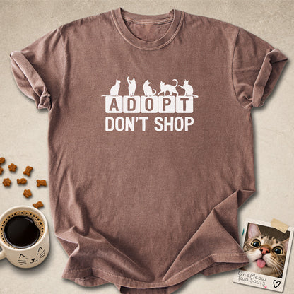 Espresso colored Comfort Colors 1717 cotton T-shirt, featuring a "Adopt Don't Shop" funny cat design illustration. One Meow Two Souls brand.