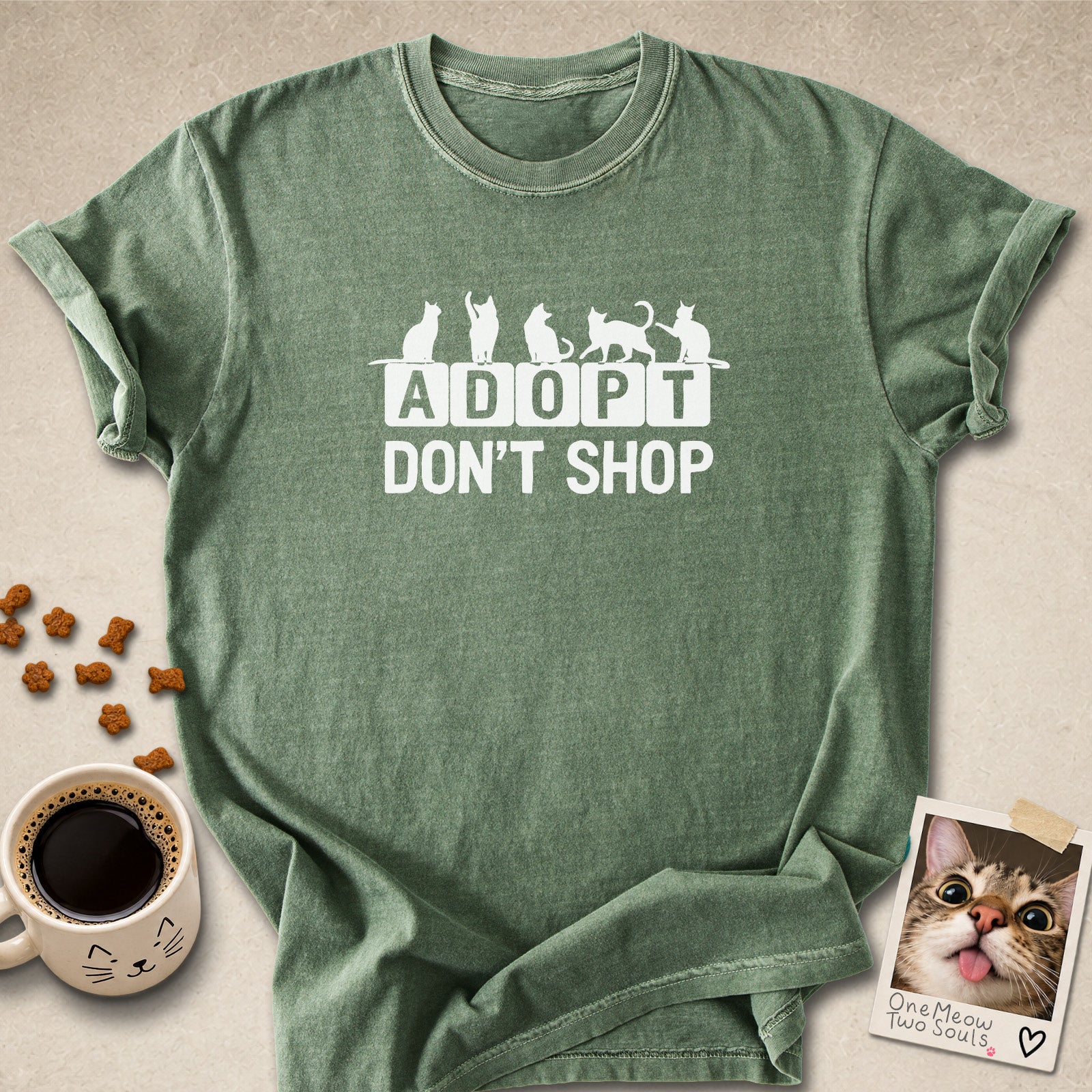 Moss colored Comfort Colors 1717 cotton T-shirt, featuring a "Adopt Don't Shop" funny cat design illustration. One Meow Two Souls brand.