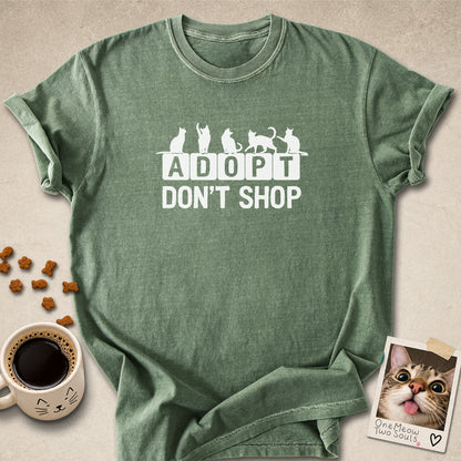 Moss colored Comfort Colors 1717 cotton T-shirt, featuring a "Adopt Don't Shop" funny cat design illustration. One Meow Two Souls brand.