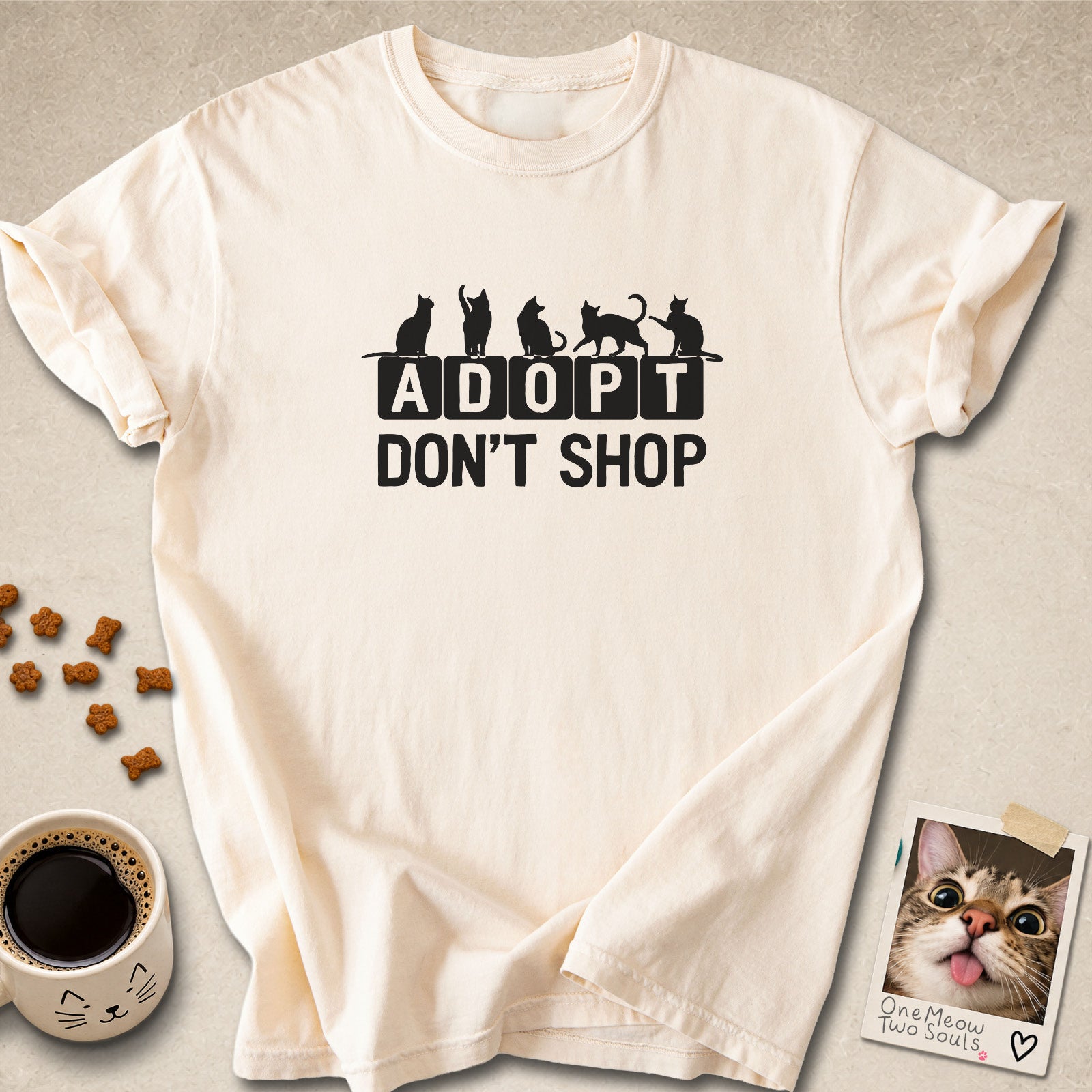 Ivory colored Comfort Colors 1717 cotton T-shirt, featuring a "Adopt Don't Shop" funny cat design illustration. One Meow Two Souls brand.