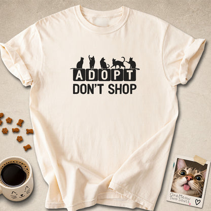 Ivory colored Comfort Colors 1717 cotton T-shirt, featuring a "Adopt Don't Shop" funny cat design illustration. One Meow Two Souls brand.
