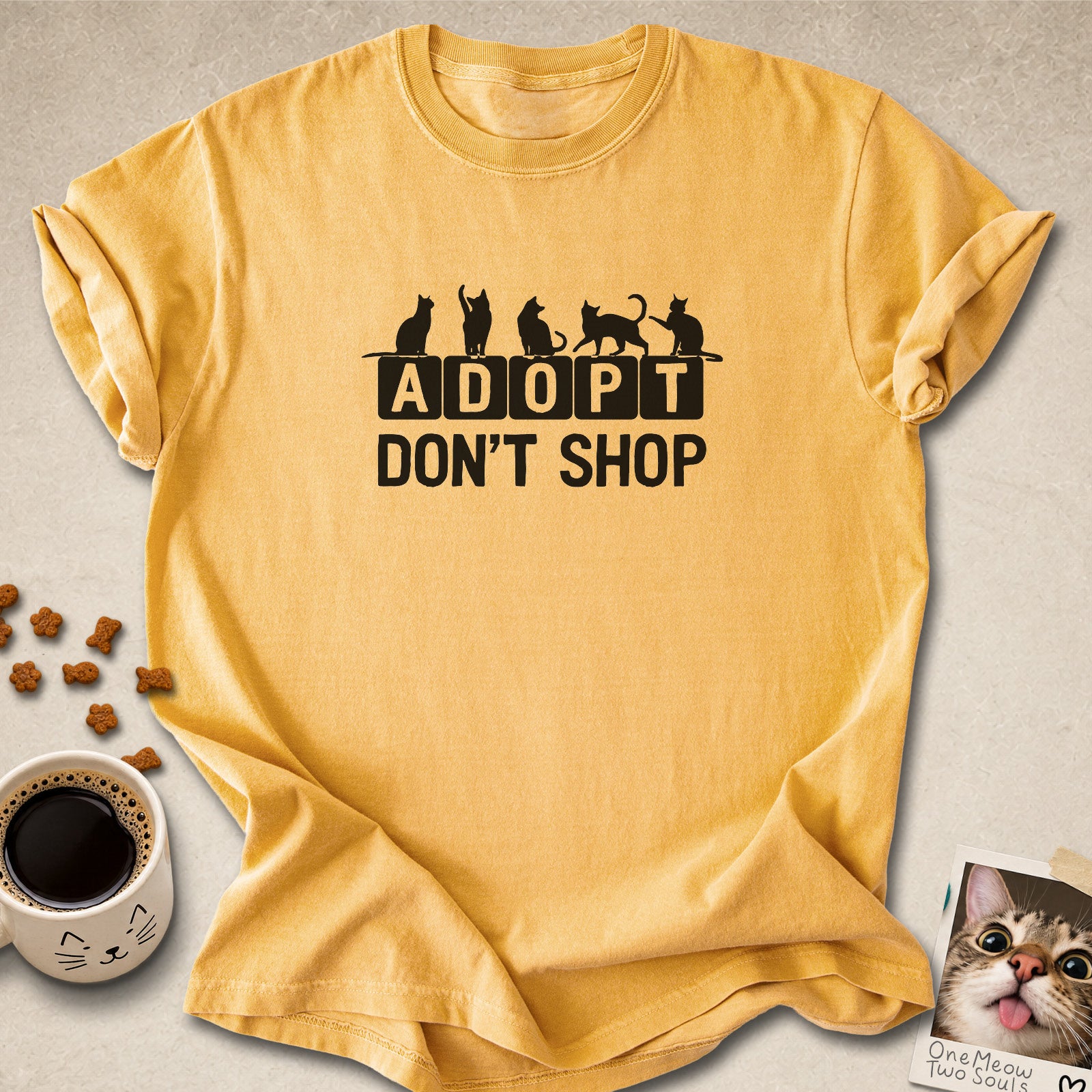 Mustard colored Comfort Colors 1717 cotton T-shirt, featuring a "Adopt Don't Shop" funny cat design illustration. One Meow Two Souls brand.