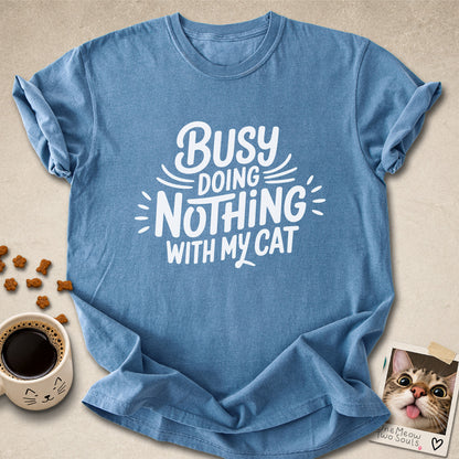 Blue Jean colored Comfort Colors 1717 cotton T-shirt, featuring a "Busy doing nothing with my cat" funny cat design illustration. One Meow Two Souls brand.