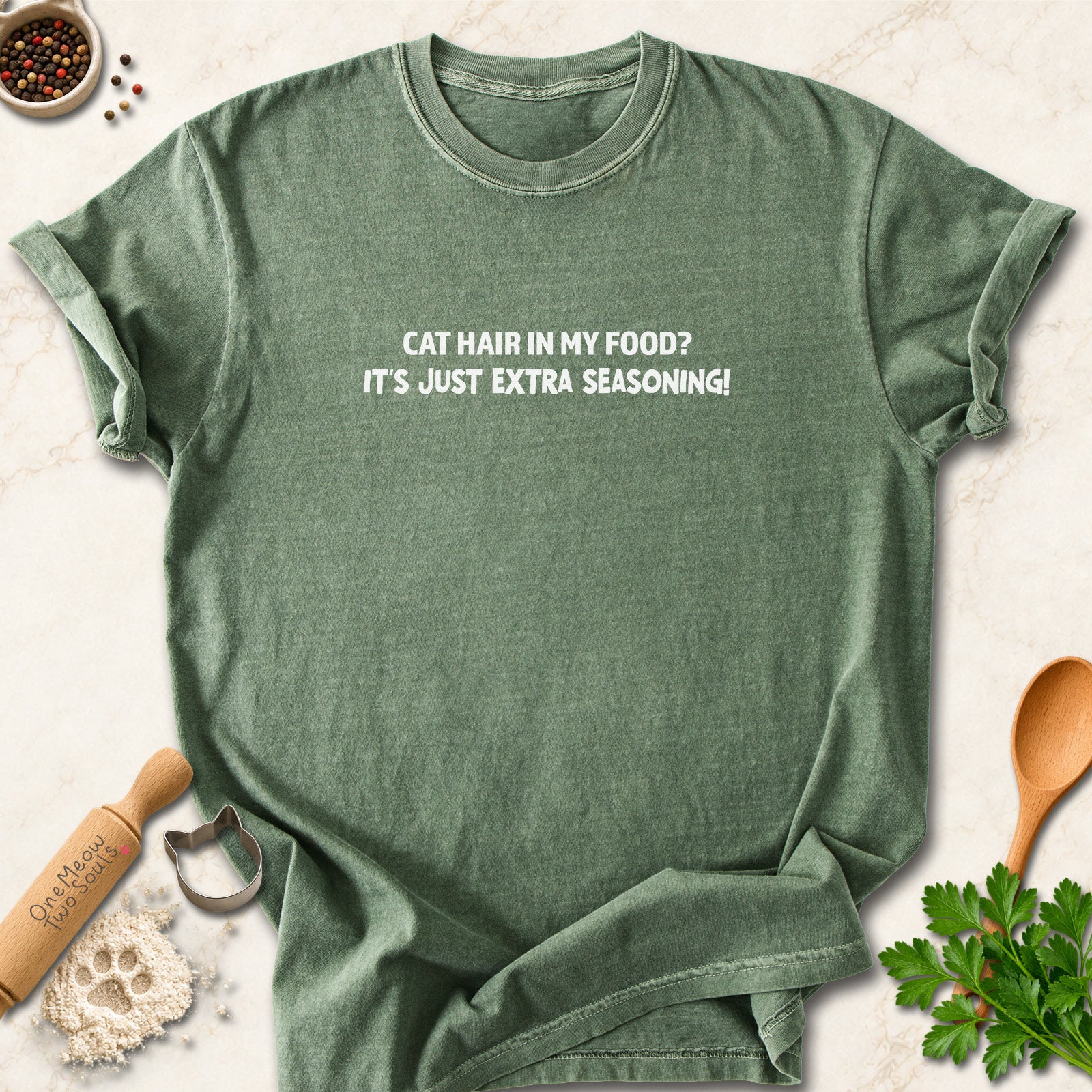 Moss colored Comfort Colors 1717 cotton T-shirt, featuring a "Cat hair in my food? It's just extra seasoning" funny cat design illustration. One Meow Two Souls brand.