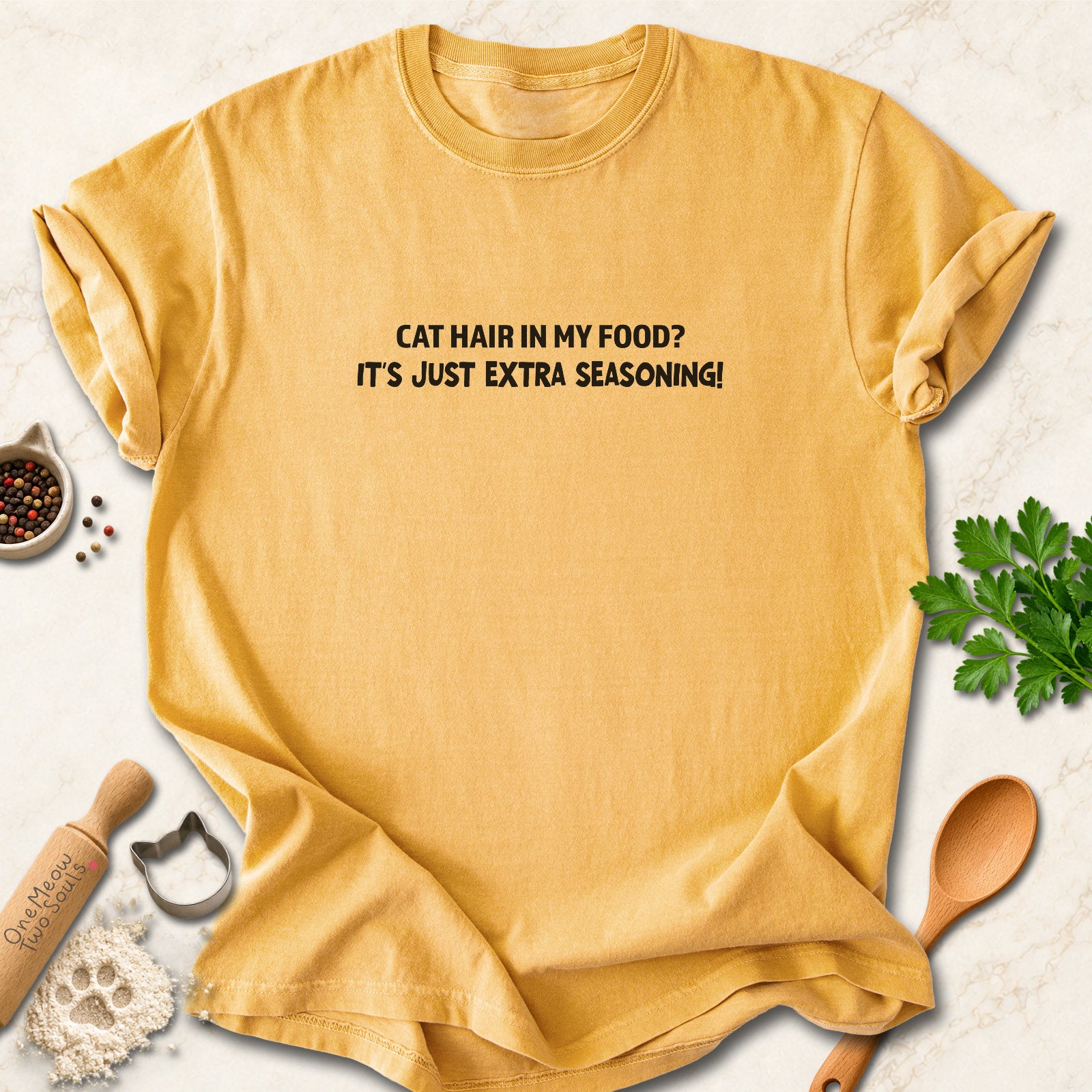 Mustard colored Comfort Colors 1717 cotton T-shirt, featuring a "Cat hair in my food? It's just extra seasoning" funny cat design illustration. One Meow Two Souls brand.