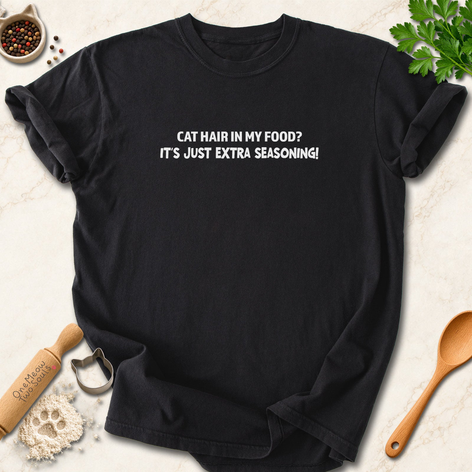 Black colored Comfort Colors 1717 cotton T-shirt, featuring a "Cat hair in my food? It's just extra seasoning" funny cat design illustration. One Meow Two Souls brand.