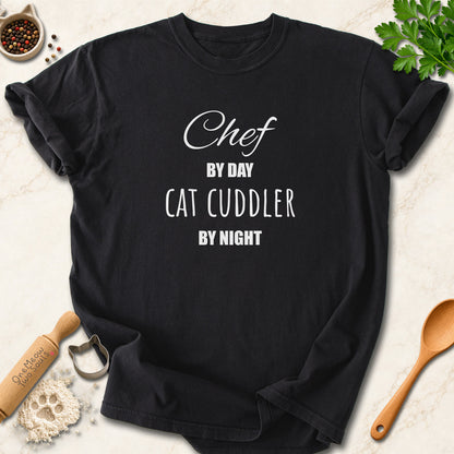 Black colored Comfort Colors 1717 cotton T-shirt, featuring a "Chef by day, cat cuddler by night" funny cat design illustration. One Meow Two Souls brand.