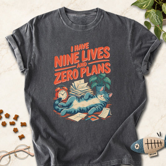 Pepper colored Comfort Colors 1717 cotton T-shirt, featuring a "i Have Nine Lives and Zero Plans" funny cat design illustration. One Meow Two Souls brand.