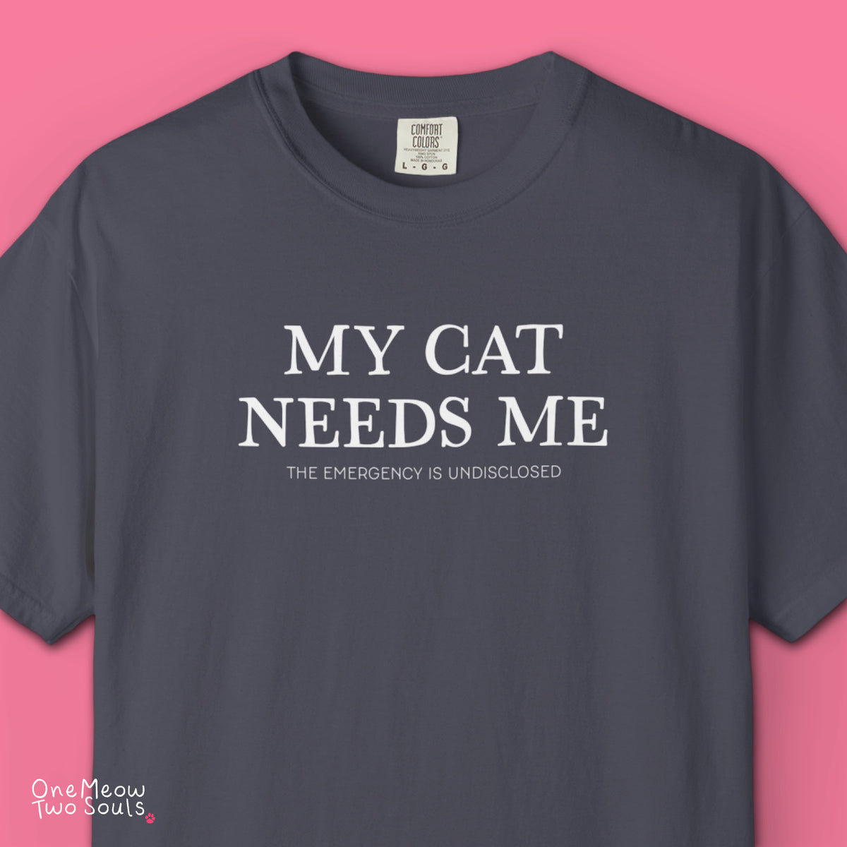 Pepper colored Comfort Colors 1717 cotton T-shirt, featuring a "My Cat Needs Me. The Emergency is Undisclosed" funny cat design illustration. One Meow Two Souls brand.