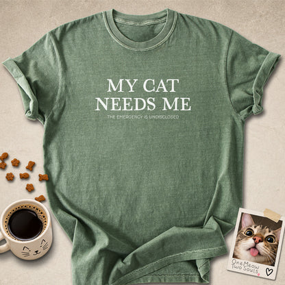Moss colored Comfort Colors 1717 cotton T-shirt, featuring a "My Cat Needs Me. The Emergency is Undisclosed" funny cat design illustration. One Meow Two Souls brand.