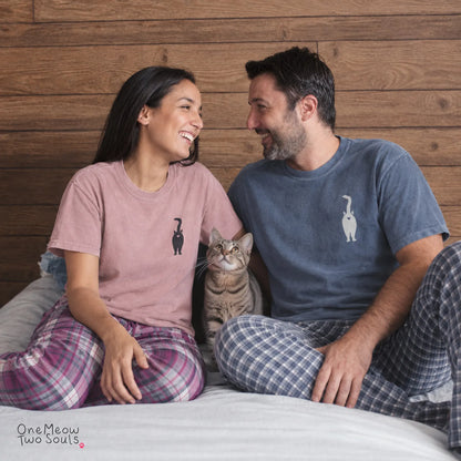 A man and woman sitting on a bed together with a tabby cat, wearing matching t-shirts and plaid pajama pants. Both shirts feature a small cat graphic on the left chest.
Blossom and Blue Jean  Comfort Colors 1717 t-shirts with a funny cat Butt design. One Meow Two Sould brand.