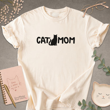 Ivory Comfort Colors 1717 t-shirt with a white graphic reading 'CAT MOM'. One Meow Two Souls brand.