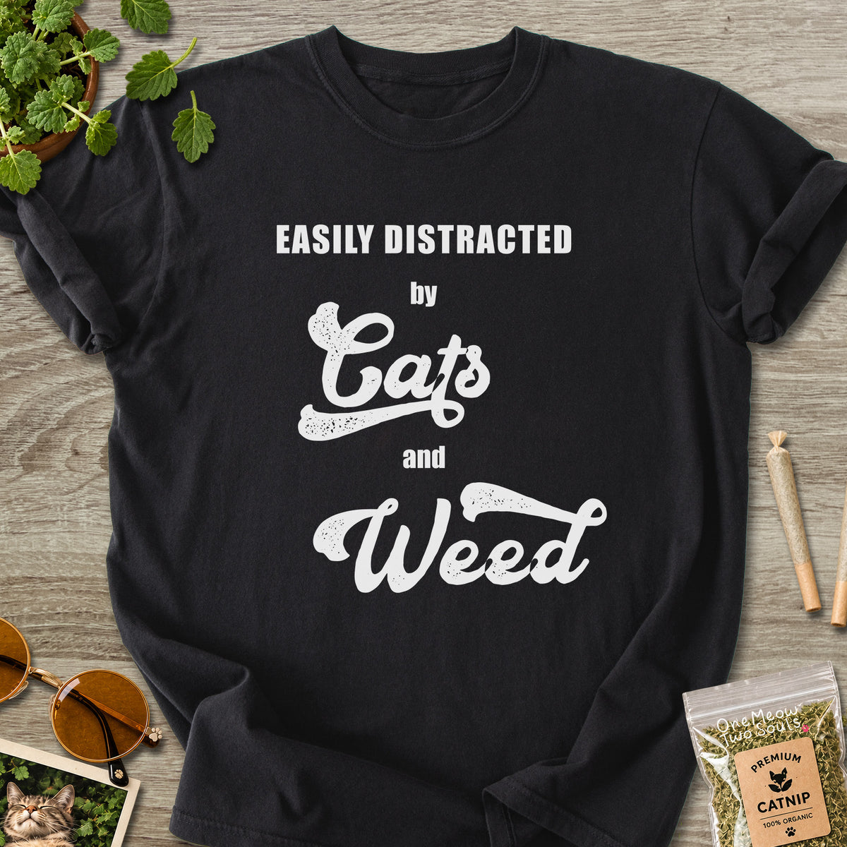Black colored Comfort Colors 1717 cotton T-shirt, featuring a "Easily Distracted by Cats and Weed" funny cat design illustration. One Meow Two Souls brand.