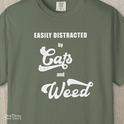 Moss colored Comfort Colors 1717 cotton T-shirt, featuring a "Easily Distracted by Cats and Weed" funny cat design illustration. One Meow Two Souls brand.