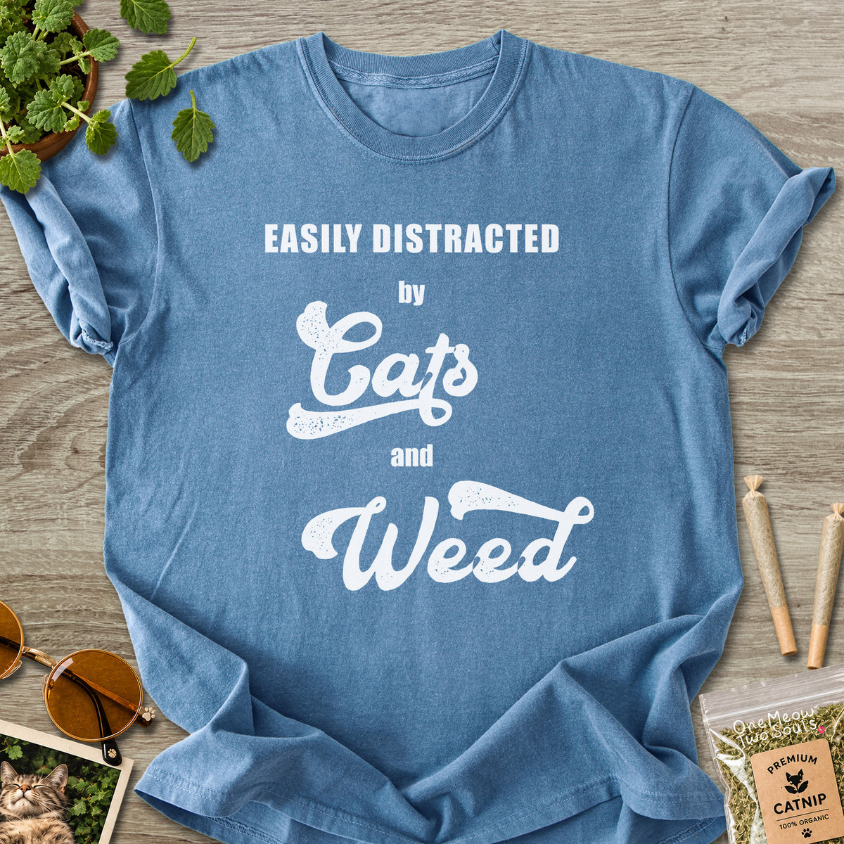 Blue Jean colored Comfort Colors 1717 cotton T-shirt, featuring a "Easily Distracted by Cats and Weed" funny cat design illustration. One Meow Two Souls brand.