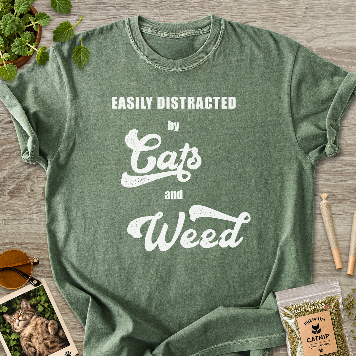 Moss colored Comfort Colors 1717 cotton T-shirt, featuring a "Easily Distracted by Cats and Weed" funny cat design illustration. One Meow Two Souls brand.