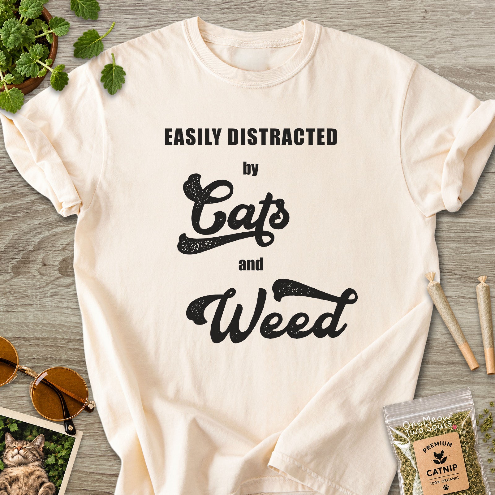 Ivory colored Comfort Colors 1717 cotton T-shirt, featuring a "Easily Distracted by Cats and Weed" funny cat design illustration. One Meow Two Souls brand.