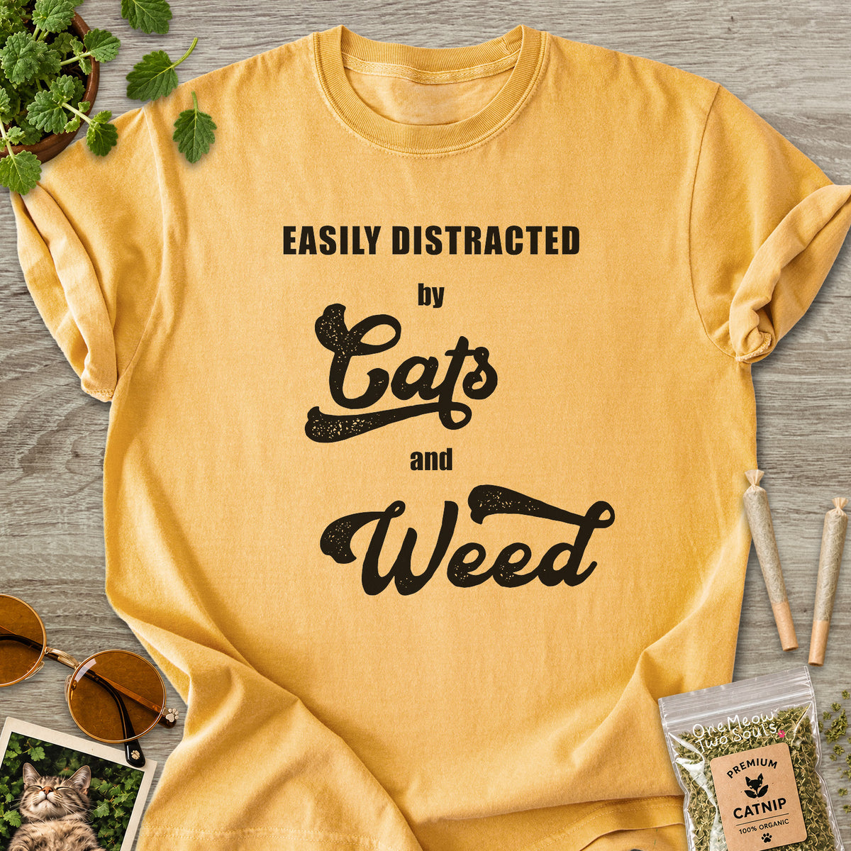 Mustard colored Comfort Colors 1717 cotton T-shirt, featuring a "Easily Distracted by Cats and Weed" funny cat design illustration. One Meow Two Souls brand.