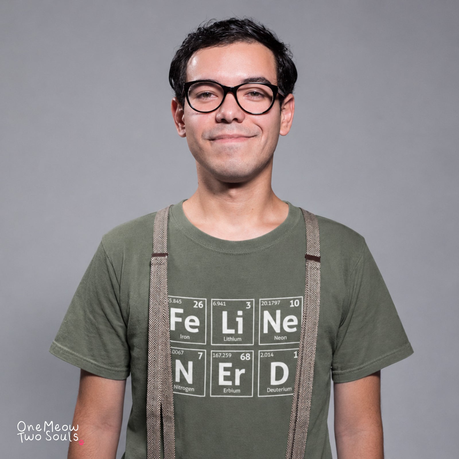 A man wearing glasses and a green t-shirt with a periodic table graphic spelling 'FELINE Nerd' in block letters, styled with suspenders against a solid gray background.
Moss color Comfort Colors 1717 T-shirt with a "Feline Nerd" chemitsry periodic table desigh. One Meow Two Souls brand.