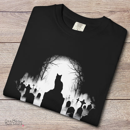 Black colored Comfort Colors 1717 cotton T-shirt, featuring a spooky graveyard Halloween cat design illustration. One Meow Two Souls brand.