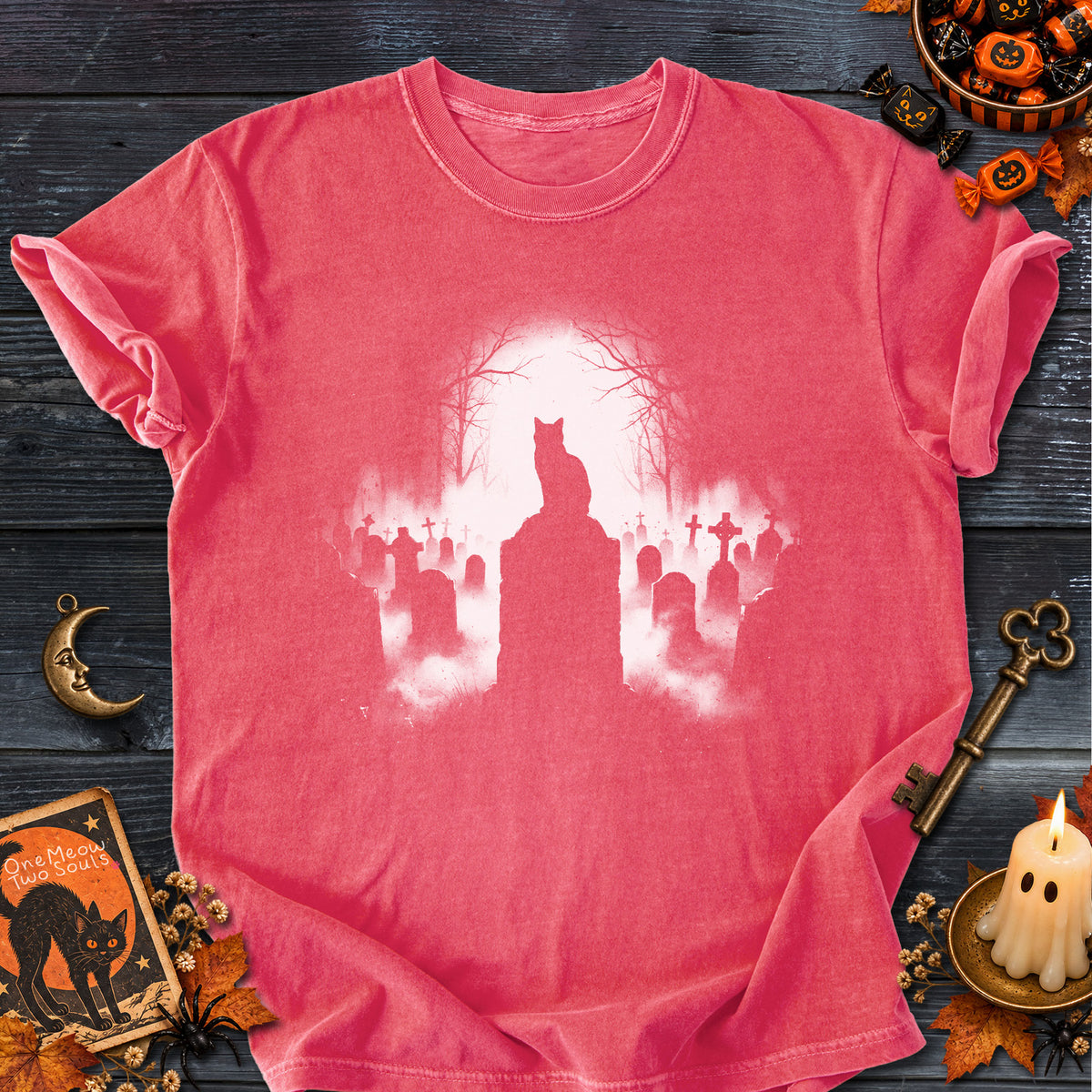 Watermelon colored Comfort Colors 1717 cotton T-shirt, featuring a spooky graveyard Halloween cat design illustration. One Meow Two Souls brand.