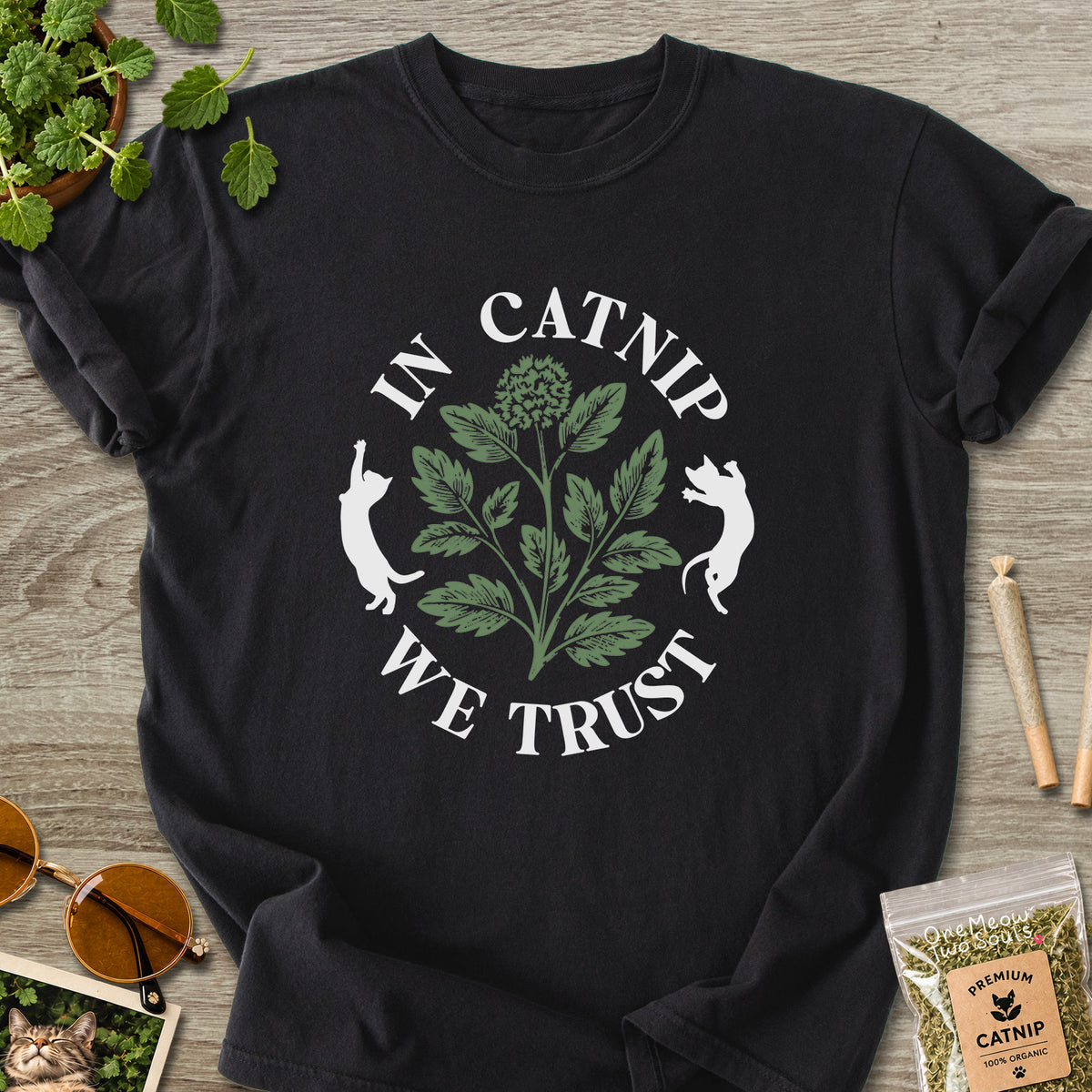 Black colored Comfort Colors 1717 cotton T-shirt, featuring a "In Catnip We Trust" funny cat design illustration. One Meow Two Souls brand.