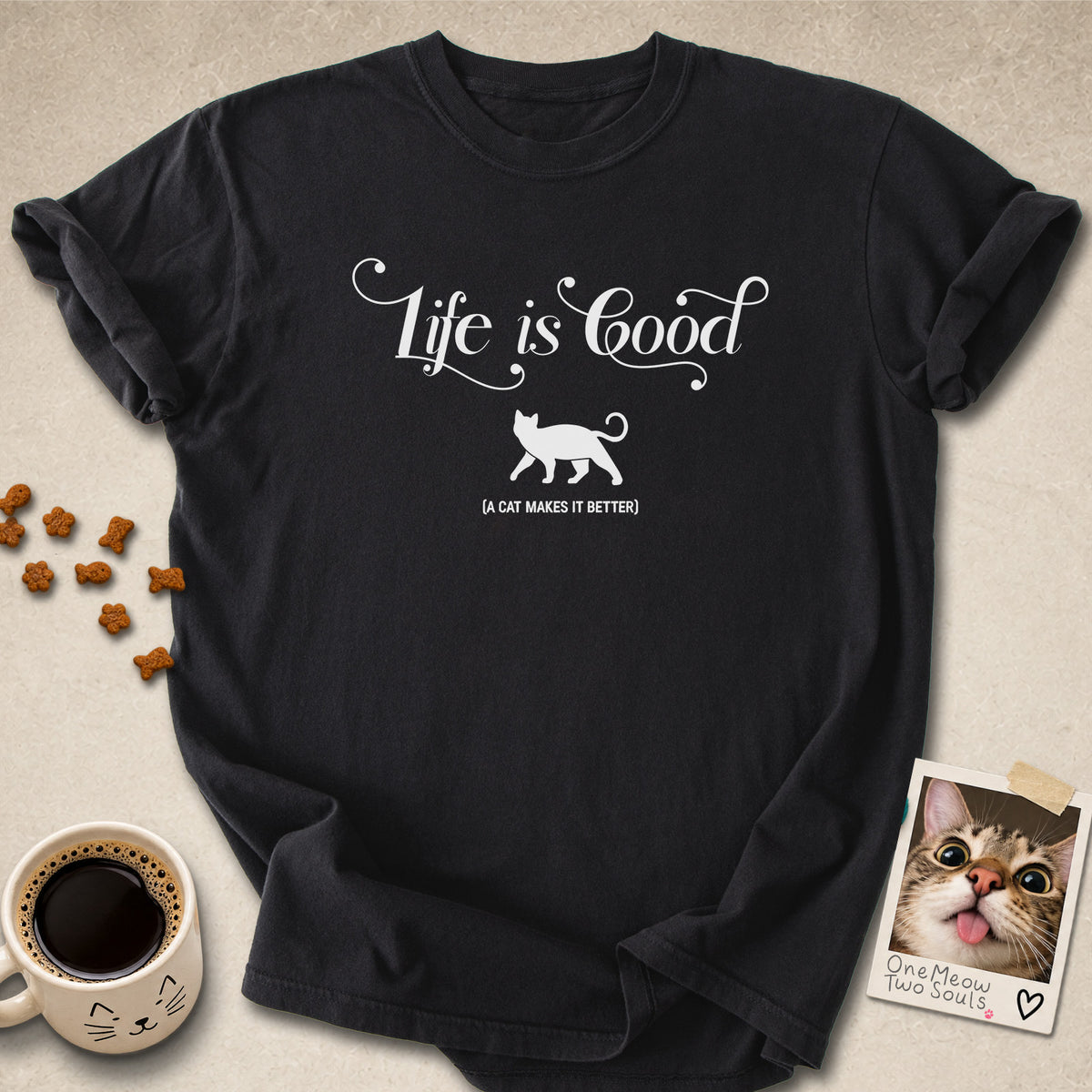 Black colored Comfort Colors 1717 cotton T-shirt, featuring a "Life is good. A cat makes it better" funny cat design illustration. One Meow Two Souls brand.