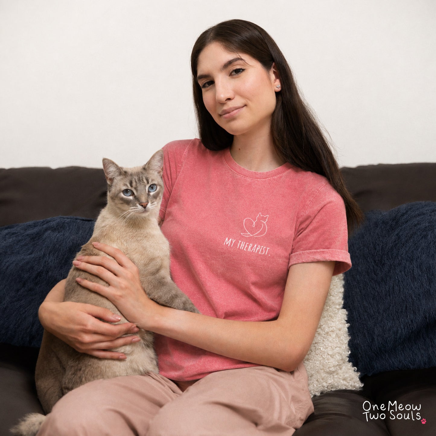 A woman sitting on a couch holding a cat, wearing a pink t-shirt with a white graphic that says 'MY THERAPIST' and 'One Meow Two Souls' in the bottom right corner.
Watermelon colored Comfort Colors 1717 t-shirt with a minimal "My Therapist" cat design. One Meow Two Souls brand.