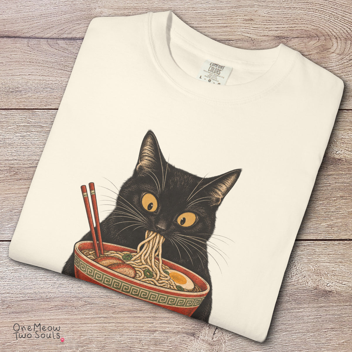 Ivory colored Comfort Colors 1717 cotton T-shirt, featuring a Black cat eating Japanese ramen noodles. Funny cat design illustration. One Meow Two Souls brand.