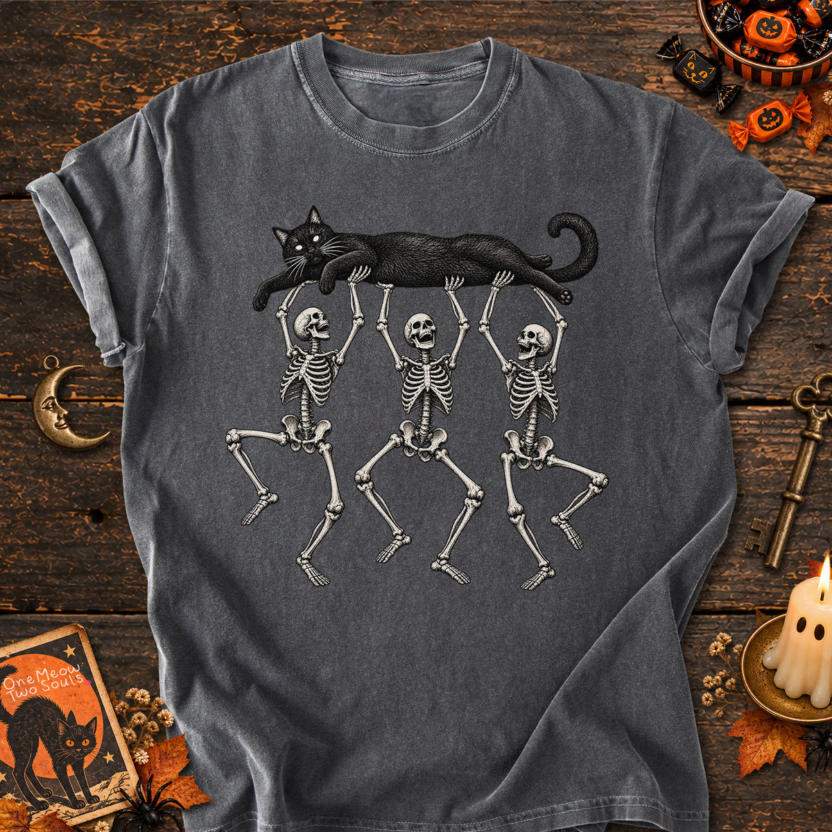 Pepper colored Comfort Colors 1717 cotton T-shirt, featuring a Black cat carried by three skeletons funny cat Halloween design illustration. One Meow Two Souls brand.