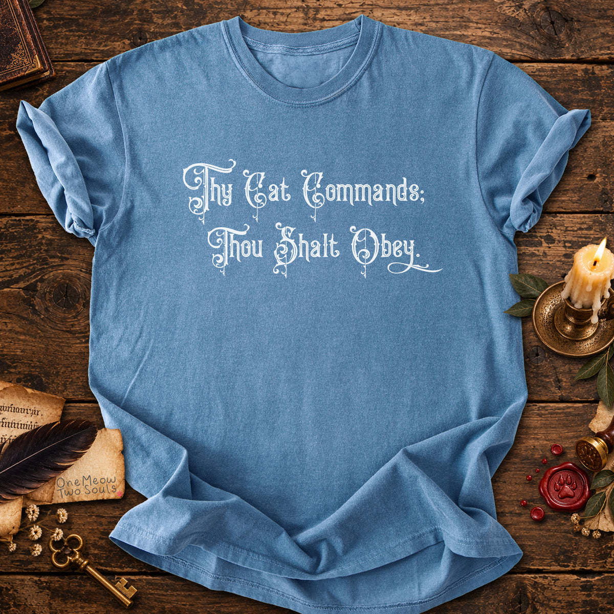 Blue Jean colored Comfort Colors 1717 cotton T-shirt, featuring a "Thy Cat Commands. Thou Shalt Obey" funny cat design illustration. One Meow Two Souls brand.