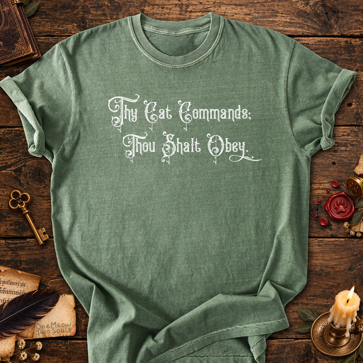 Moss colored Comfort Colors 1717 cotton T-shirt, featuring a "Thy Cat Commands. Thou Shalt Obey" funny cat design illustration. One Meow Two Souls brand.