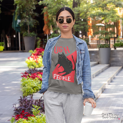 A woman wearing a graphic t-shirt with a black cat silhouette and the text 'UGH PEOPLE' in red and white, styled with a denim jacket and sweatpants in an outdoor urban setting.
Grey colored Comfort Colors 1717 cotton T-shirt, presenting a "Ugh People" funny cat design. One Meow Two Souls brand.
