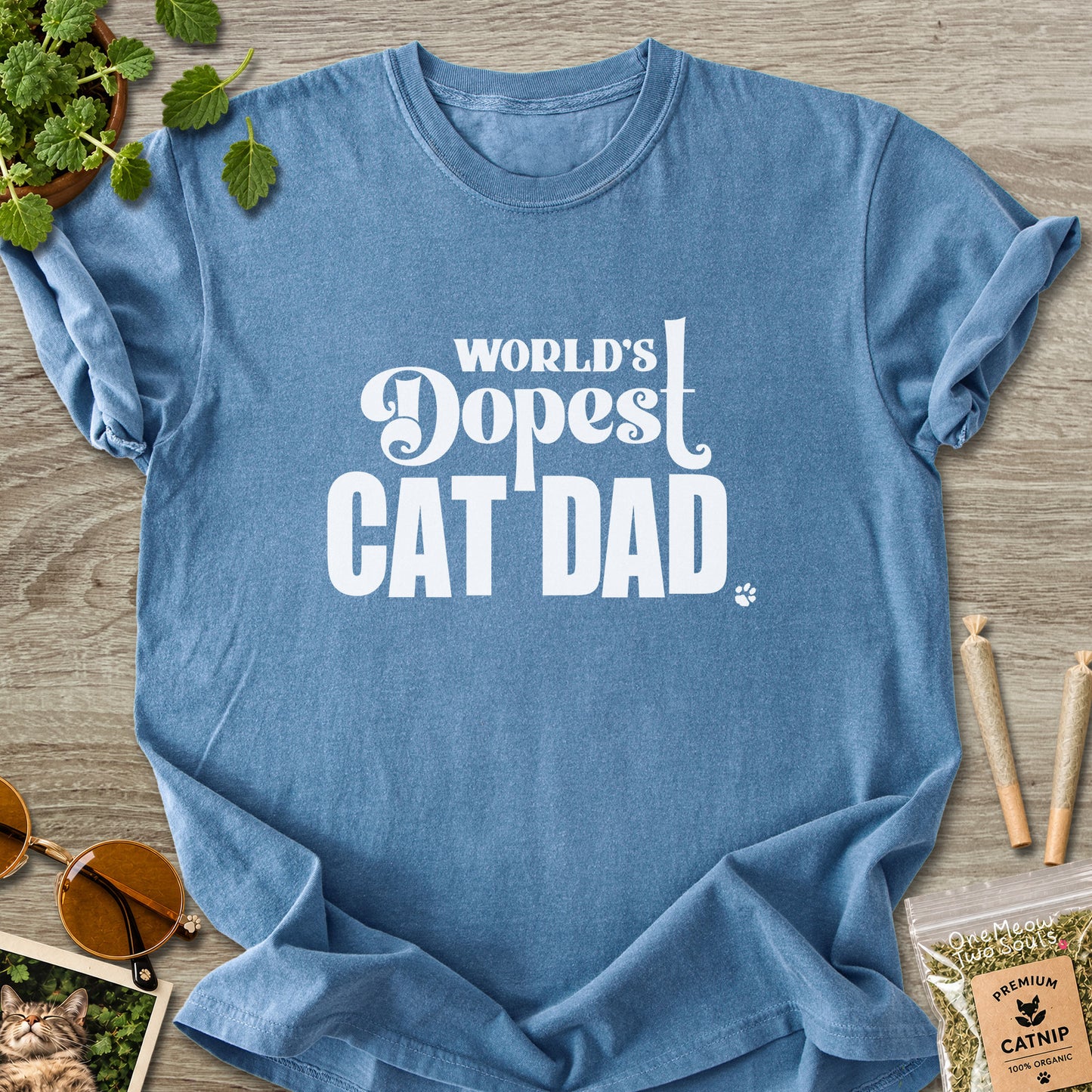 Blue Jean colored Comfort Colors 1717 cotton T-shirt, featuring a "World's Dopest Cat Dad" funny cat design illustration. One Meow Two Souls brand.
