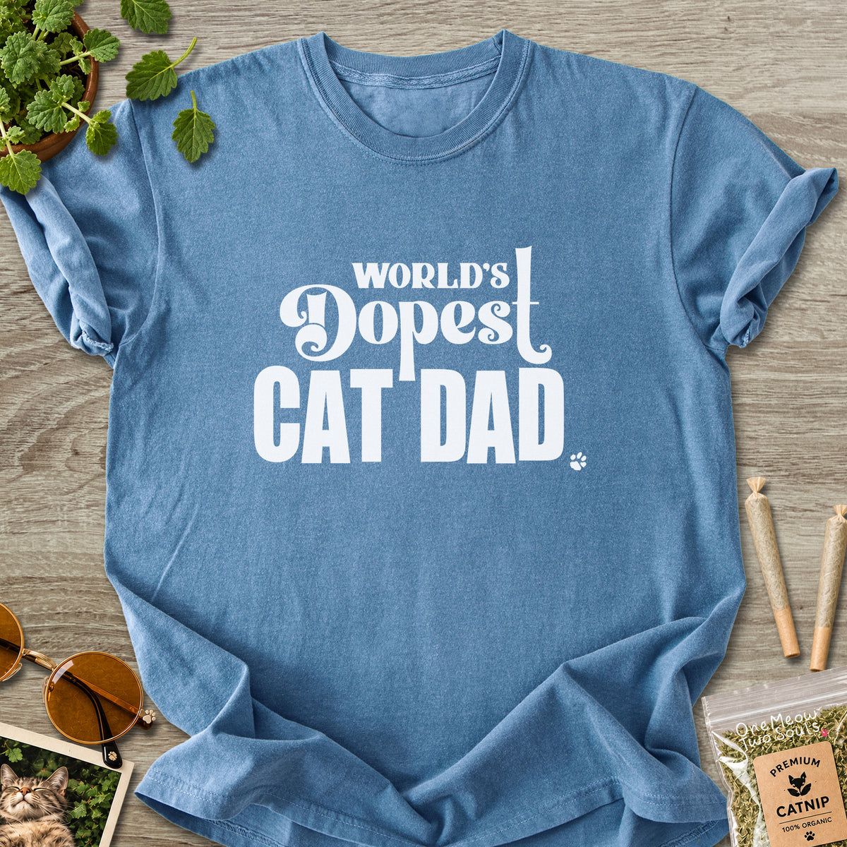 Blue Jean colored Comfort Colors 1717 cotton T-shirt, featuring a "World's Dopest Cat Dad" funny cat design illustration. One Meow Two Souls brand.