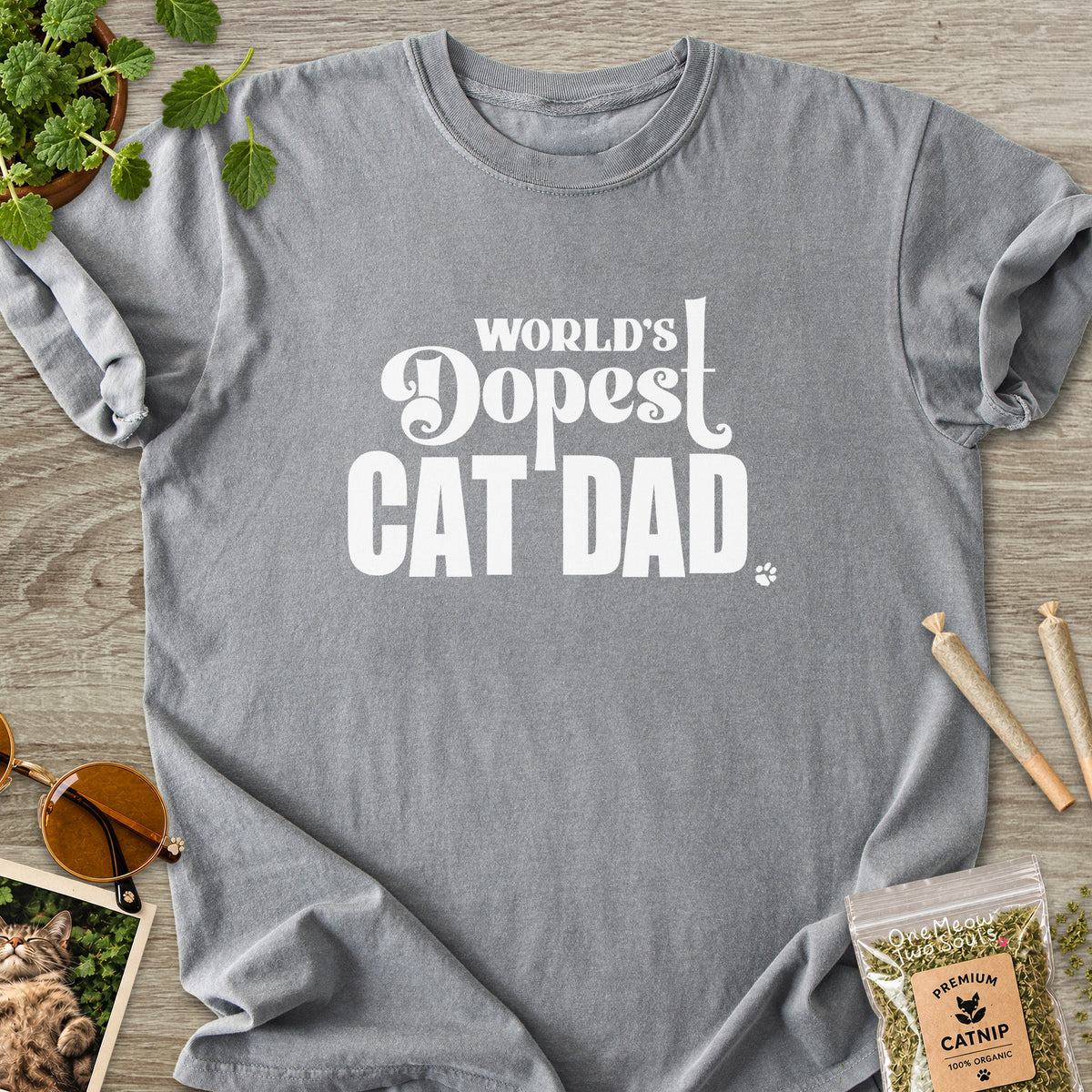 Grey colored Comfort Colors 1717 cotton T-shirt, featuring a "World's Dopest Cat Dad" funny cat design illustration. One Meow Two Souls brand.