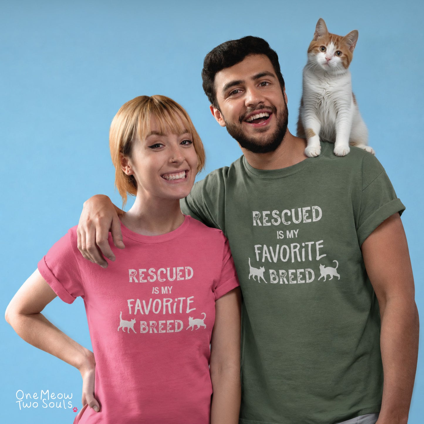 A man and a woman wearing matching graphic t-shirts with the text 'RESCUED IS MY FAVORITE BREED' and small cat silhouettes, with a white and orange cat sitting on the man's shoulder against a solid blue background.
Crunchberry and Moss colored Comfort Colors 1717 cotton T-shirts, featuring a "Rescued is my favorite breed" funny cat design. One Meow Two Souls brand.