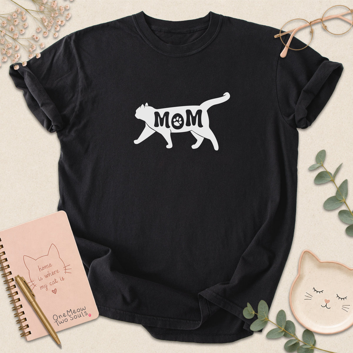Black color Comfort Colors 1717 short-sleeve t-shirt with a white cat silhouette and the word 'MOM' across the chest. One Meow Two Souls brand.