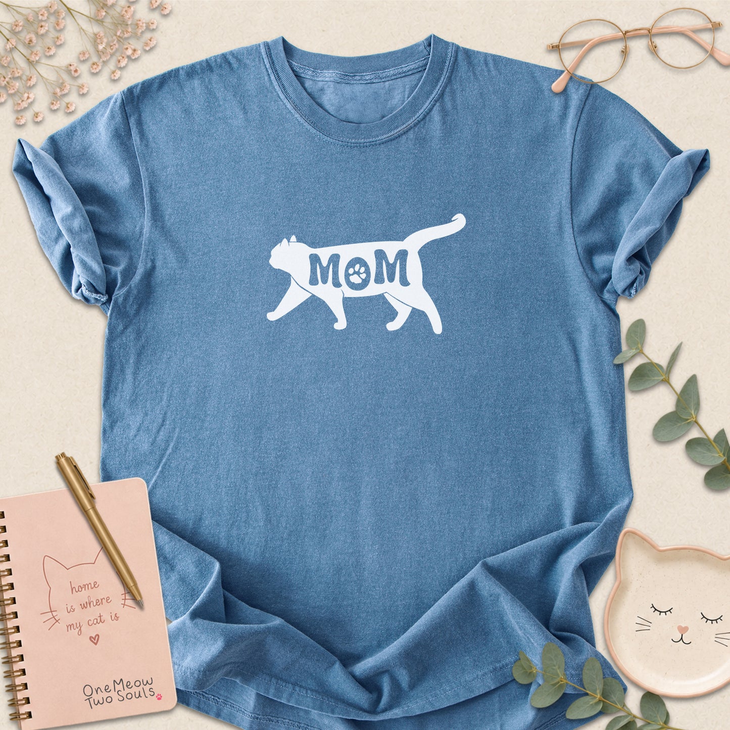 Blue Jean color Comfort Colors 1717 short-sleeve t-shirt with a white cat silhouette and the word 'MOM' across the chest. One Meow Two Souls brand.
