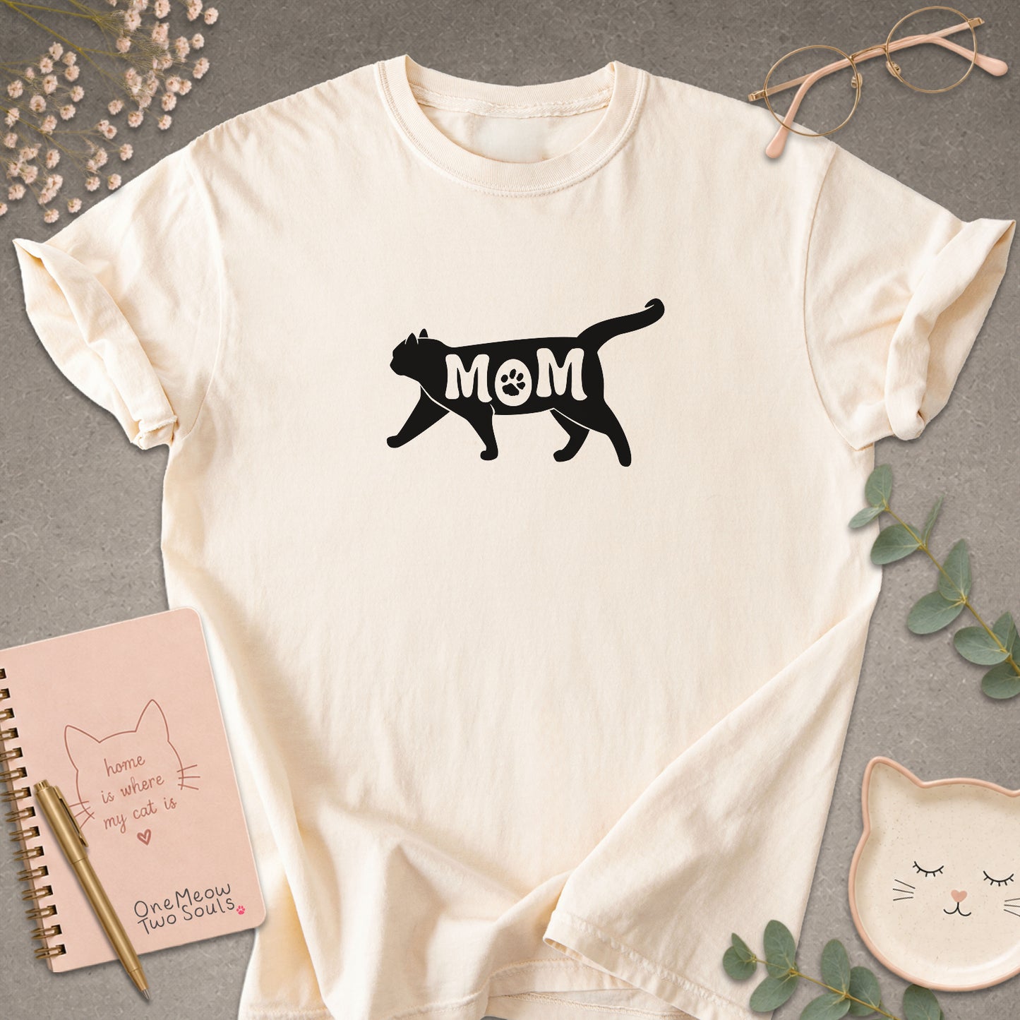 Ivory color Comfort Colors 1717 short-sleeve t-shirt with a white cat silhouette and the word 'MOM' across the chest. One Meow Two Souls brand.